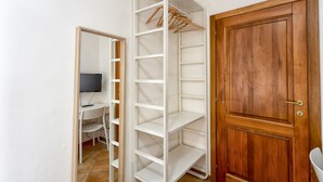 A room with a wooden door, a white shelving unit, and a desk with a television. - Zannoni Apartments (Florence)