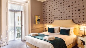 Ein Hotelzimmer mit Bett, Nachttisch, Stuhl und Blick auf den Balkon.