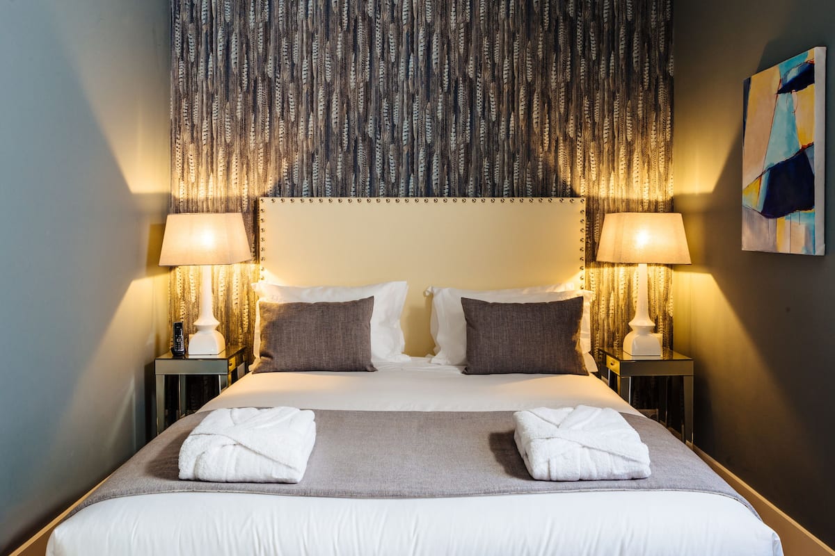 Een hotelkamer met een groot bed, twee bedlampen en een hoofdbord met een patroon.