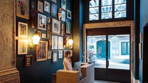 Ein Empfangsbereich mit Rezeptionistin am Schreibtisch, gerahmten Kunstwerken an den Wänden und Blick auf die Straße durch ein großes Fenster.