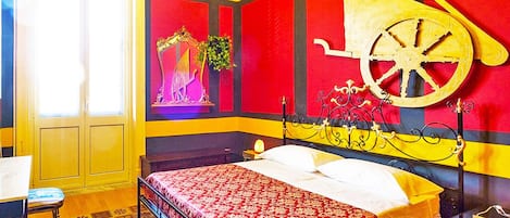 A bedroom with a bed, a nightstand, a chair, and a window with curtains.