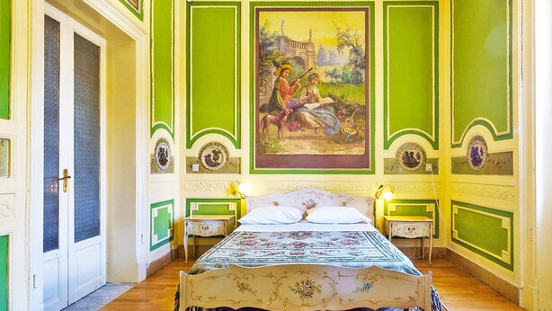 A room with a bed, two bedside tables, a painting on the wall, and a patterned rug. - Hollywood Inn Palermo Rooms (Palermo)