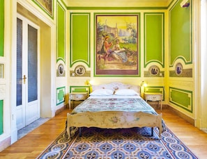 A room with a bed, two bedside tables, a painting on the wall, and a patterned rug. - Hollywood Inn Palermo Rooms (Palermo)