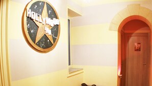 A hallway with a star-shaped sign reading "Hollywood Inn," a small window, a tiled floor, and a door with a poster. - Hollywood Inn Palermo Rooms (Palermo)