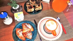 A breakfast table with croissants, a plate of cake, a glass of orange juice, and a cup of coffee. - Hollywood Inn Palermo Rooms (Palermo)
