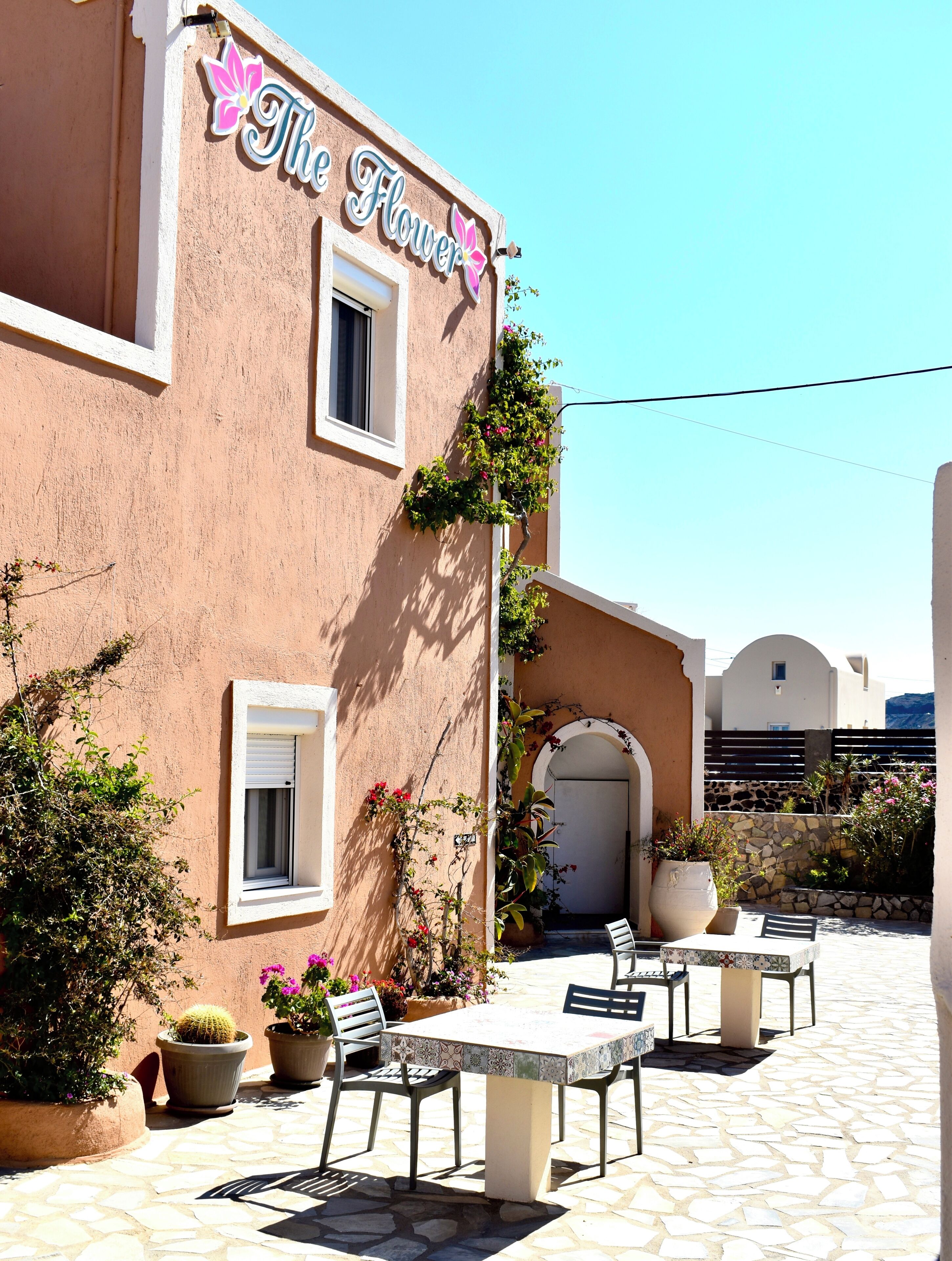A building with a sign reading 'The Flower' and a patio with outdoor seating.