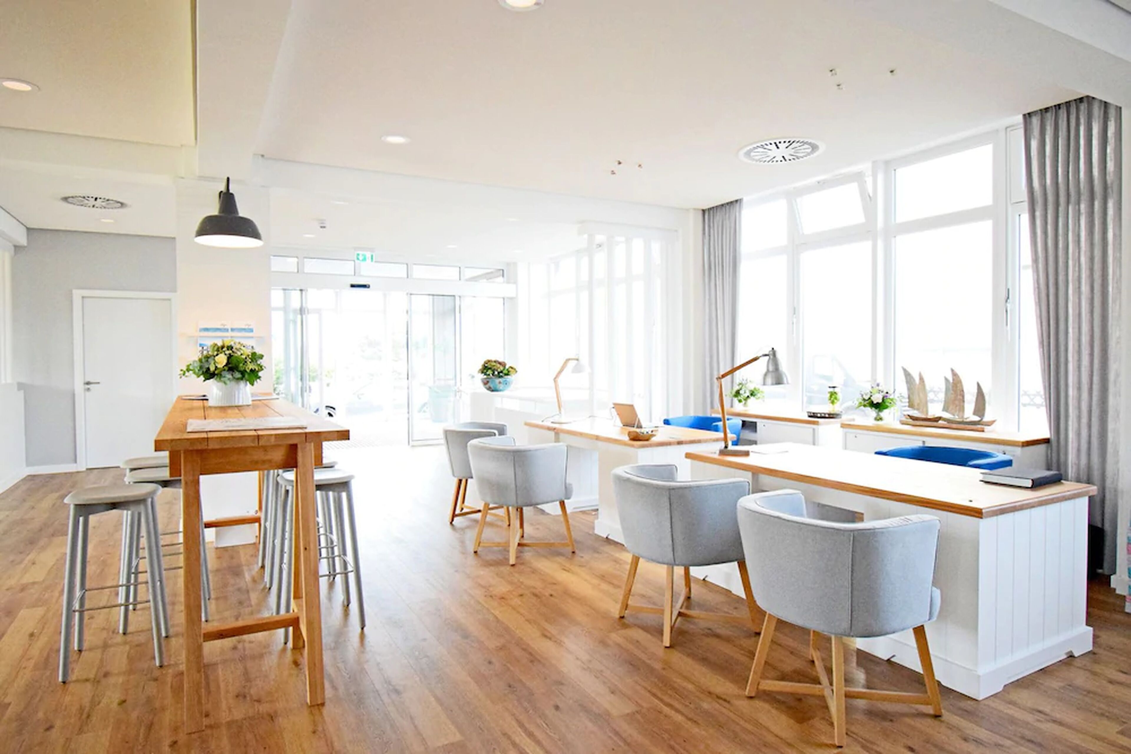 A modern kitchen with wooden countertops, bar stools, and a large window with curtains.