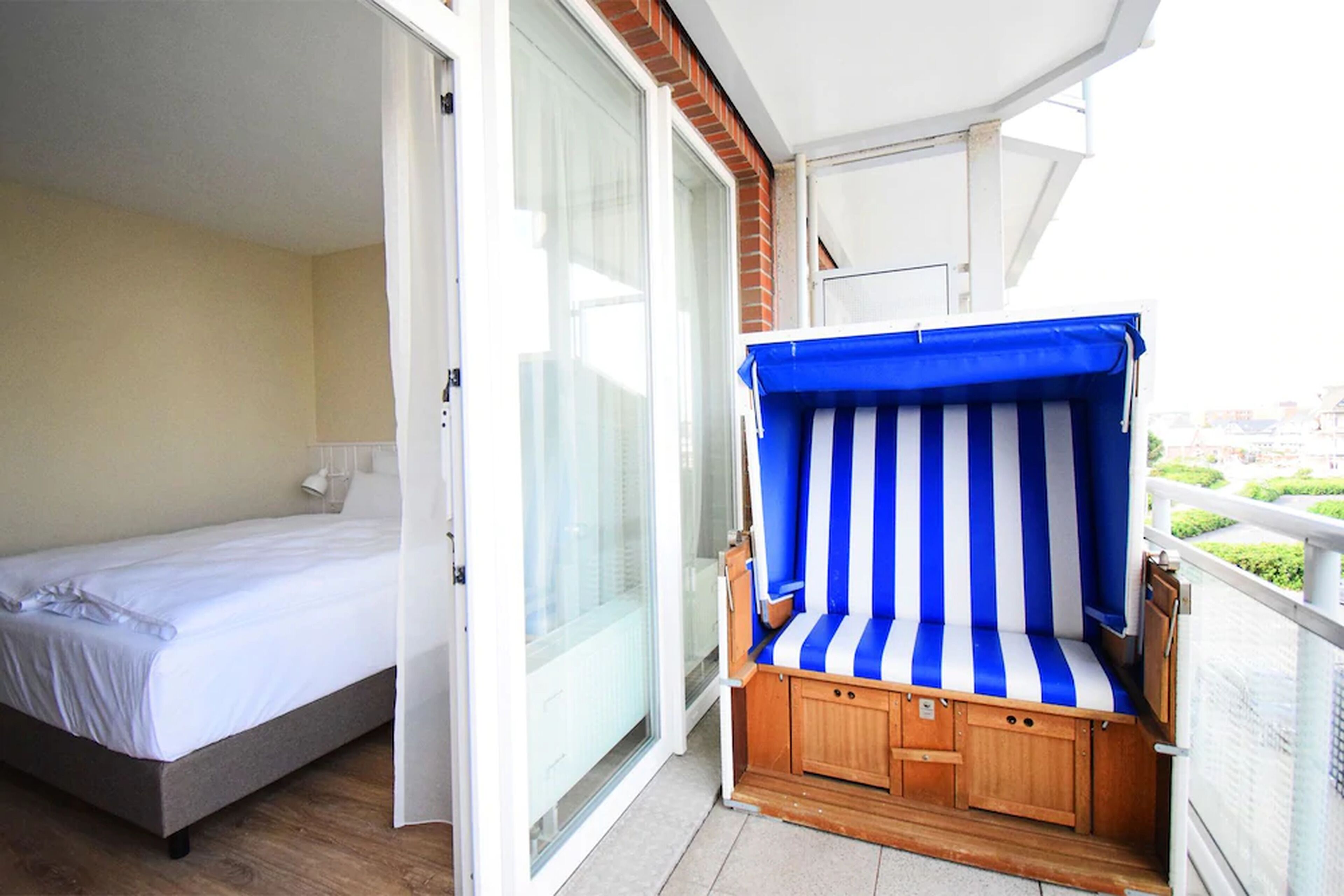 Un balcon avec un lit et une chaise longue rayée.