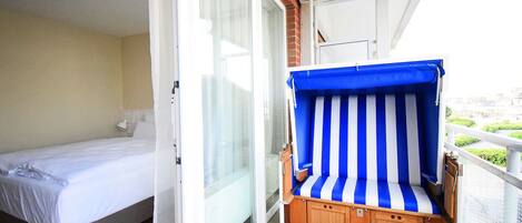Un balcon avec un lit et une chaise longue rayée.