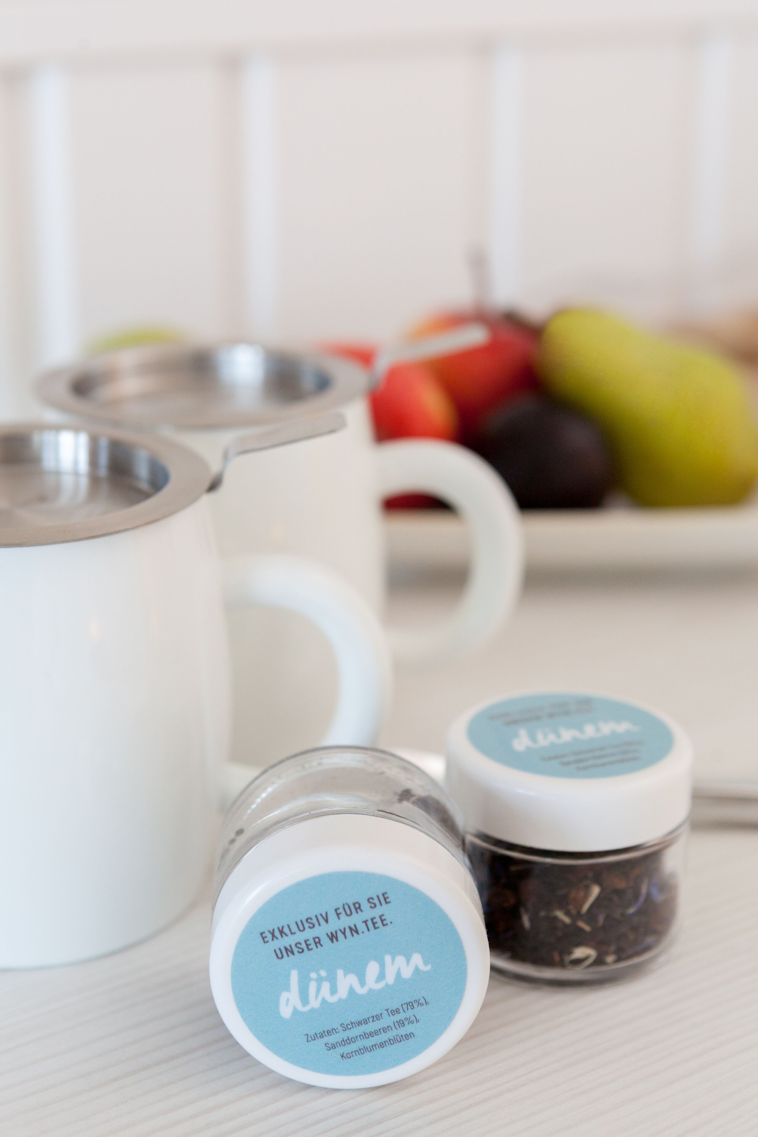 Une cuisine avec des tasses blanches, une bouilloire et des boîtes à thé.