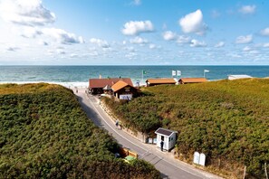 A coastal road with buildings and a small kiosk. - Wyn. Strandhotel Sylt (Sylt)