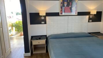 Un dormitorio con una cama grande, dos mesitas de noche, una lámpara de pared y una obra de arte enmarcada sobre la cama.