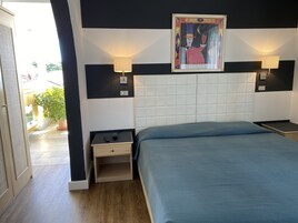 Un dormitorio con una cama grande, dos mesitas de noche, una lámpara de pared y una obra de arte enmarcada sobre la cama.