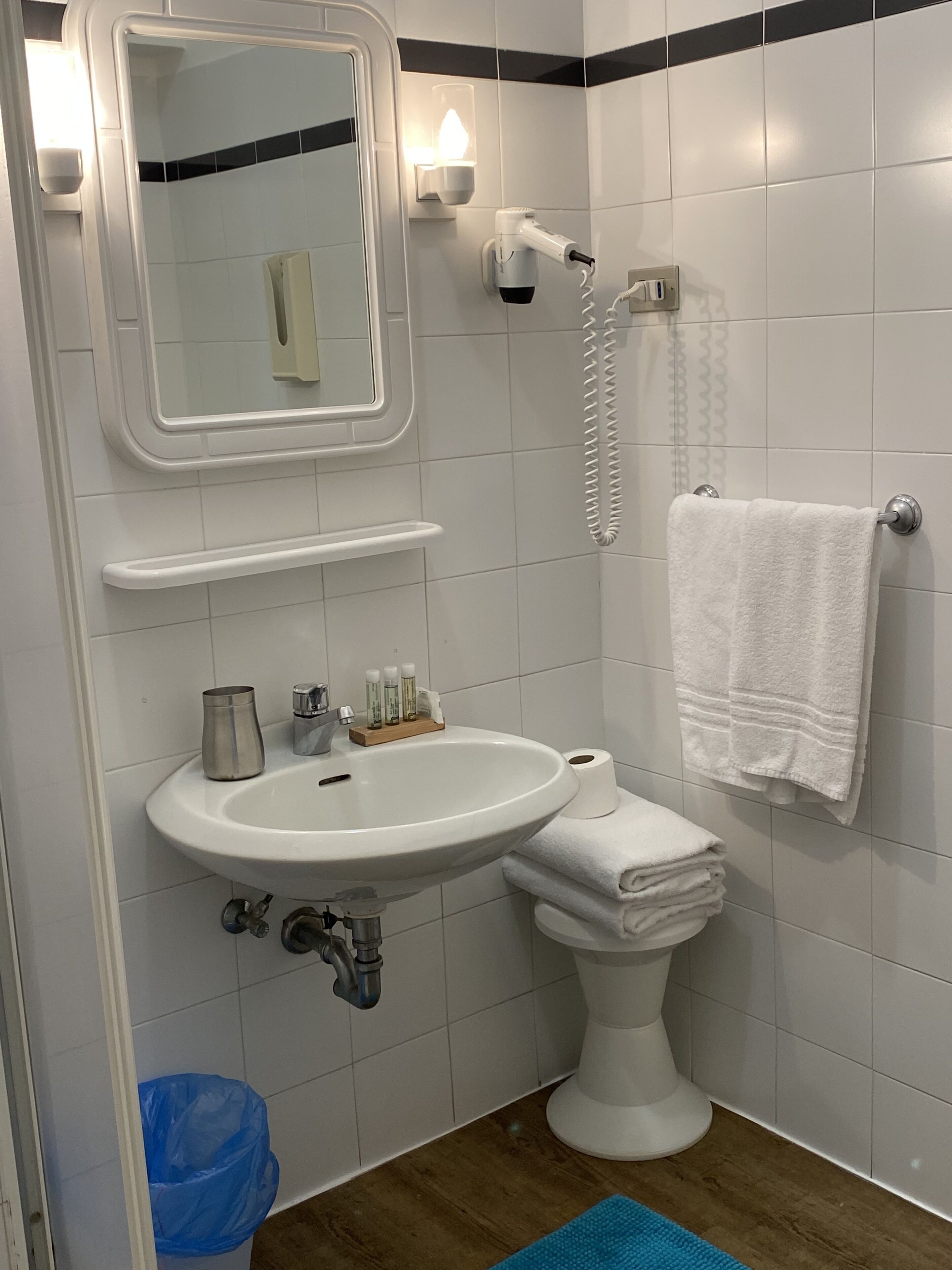 A bathroom with a white sink, mirror, and towel rack.