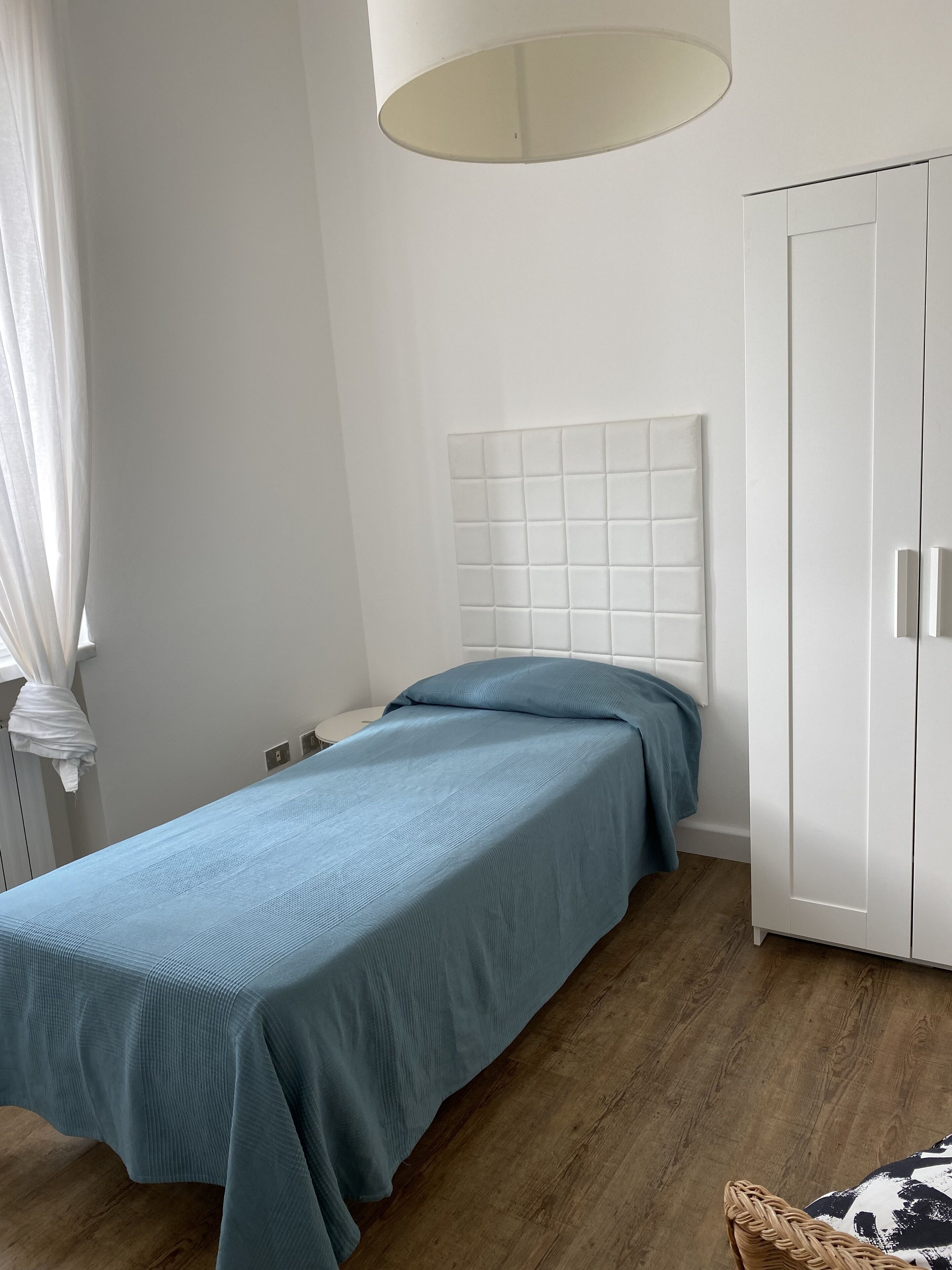 Un dormitorio con cama, armario y lámpara colgante.