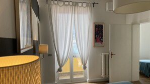 Een slaapkamer met een bed, een raam met gordijnen, een radiator en een schilderij aan de muur.