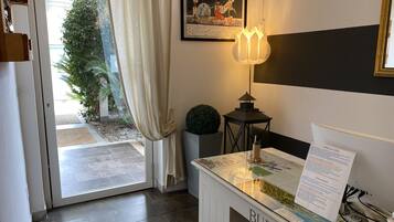 Ein Hotelrezeptionsbereich mit einem Schreibtisch, einem gerahmten Bild, einer Lampe und Blick ins Freie.