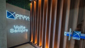 Entrada de un hotel con un cartel que dice 'Opuka Hotel' y 'Volte Sempre'.