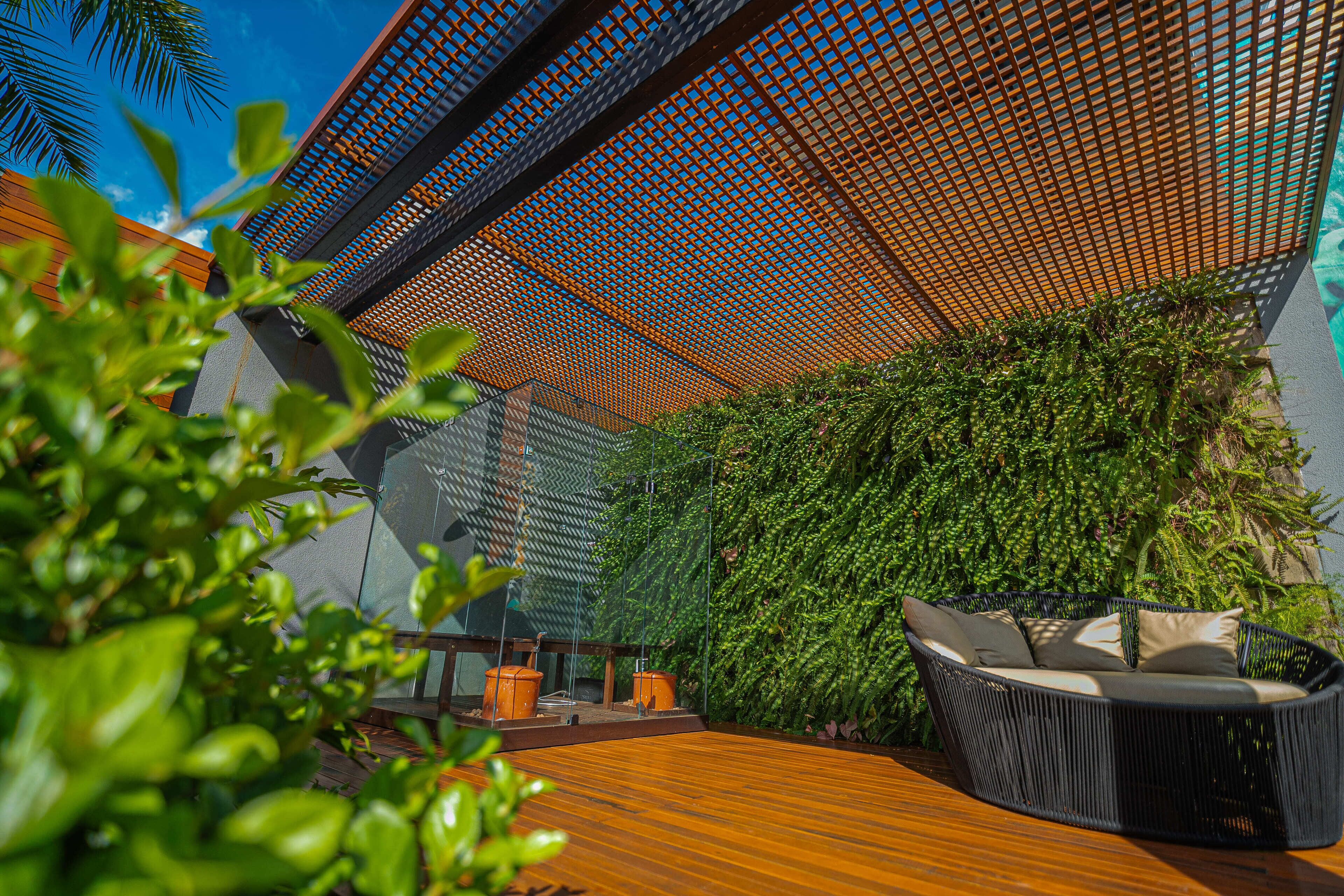A modern outdoor seating area with a wooden deck, a woven sofa, and a vertical garden wall.