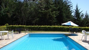 A rectangular swimming pool with a tiled edge, surrounded by stone tiles. - Chácara Marson (Mandaguaçu)