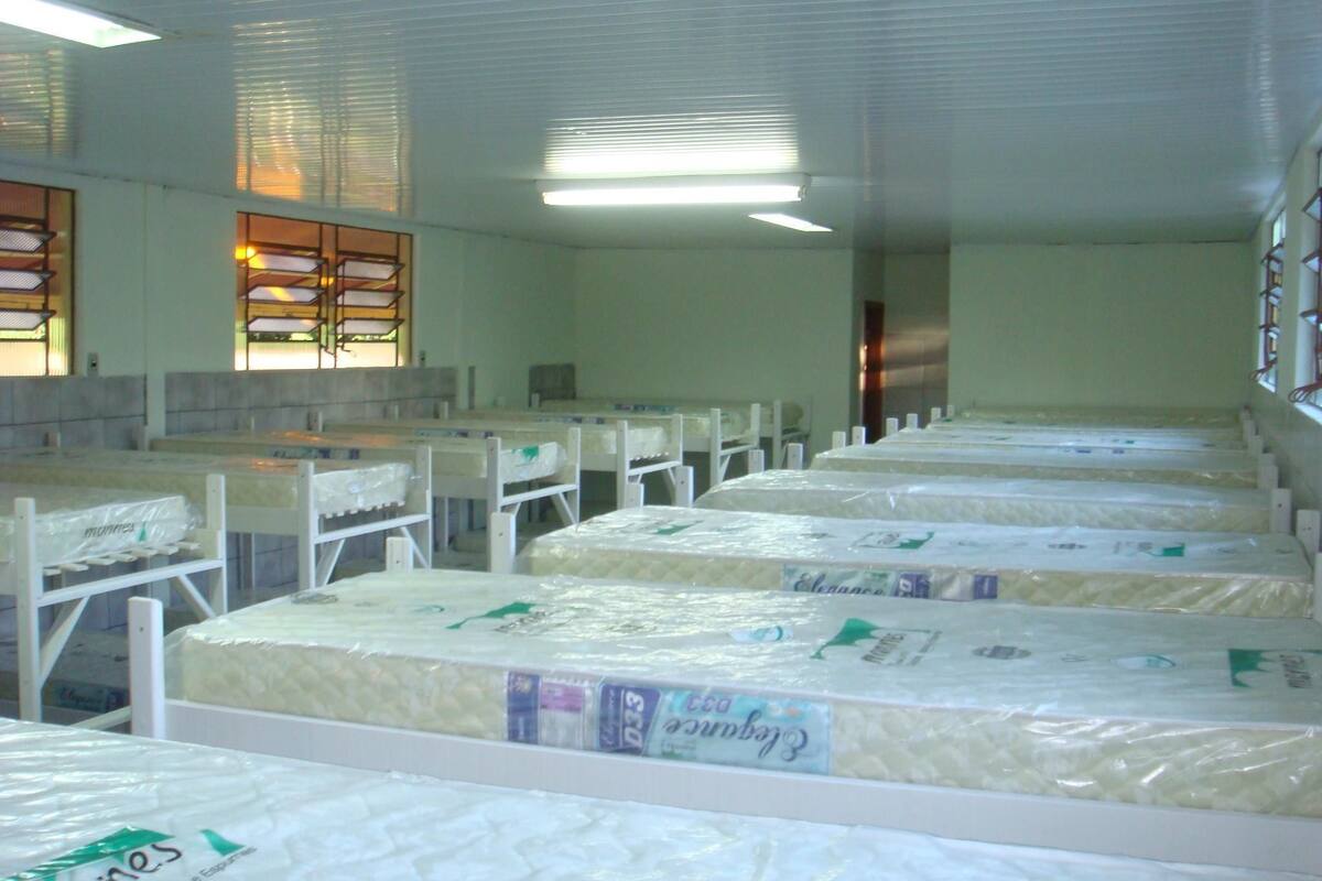 A room with rows of beds, each covered with a mattress labeled 'Elegance'.