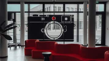 A modern lobby with red seating, a large window, and a unique wall art installation.