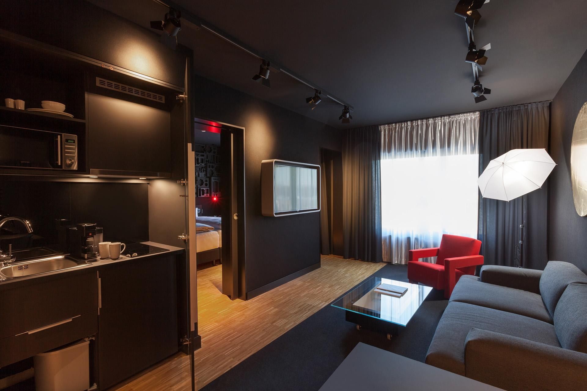 A modern living room with a sofa, a red chair, a coffee table, and a television.