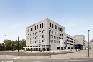 A modern hotel with a flat facade, multiple windows, and a covered outdoor seating area. - Ernst Leitz Hotel Wetzlar (Wetzlar)