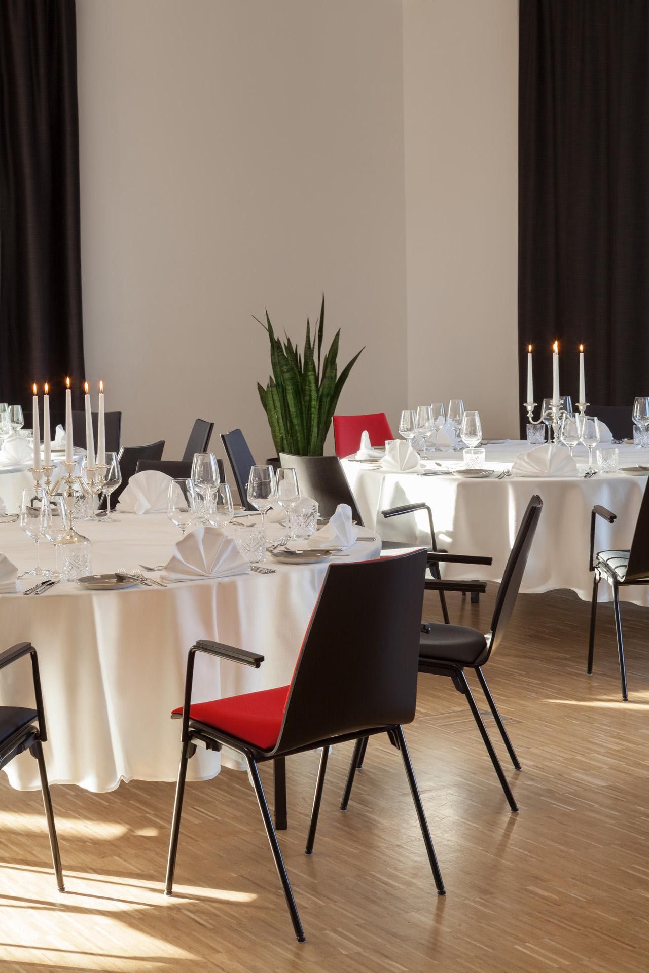 A dining area with tables set for a meal, chairs, and candles.