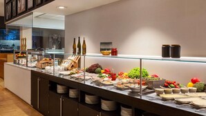 A buffet with various food items and condiments, a glass display case, and a wall with framed pictures. - Ernst Leitz Hotel Wetzlar (Wetzlar)
