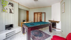 Quarto com mesa de bilhar, televisão e lareira.