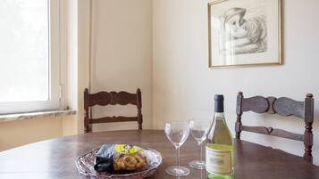 A dining table with a bottle of wine, two wine glasses, and a bowl of snacks.