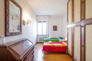 Una habitación con dos camas, un aparador, un espejo grande y un radiador.