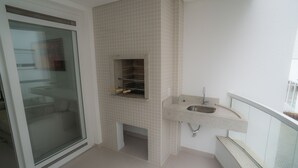 A bathroom with a glass door, a tiled wall, a sink, and a small shelf. - Praia dos Ingleses Belo Recanto da Ilha (Florianópolis)