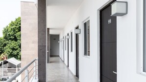 A long, narrow corridor with a tiled floor, white walls, and a series of doors on one side. - Nova Hotel (Cadereyta Jimenez)