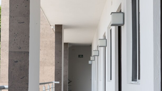 A corridor with a tiled floor, white walls, and a series of windows on one side. - Nova Hotel (Cadereyta Jimenez)