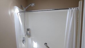 A bathroom with a shower, toilet, and granite countertop.