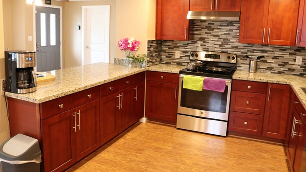 A kitchen with wooden cabinets, a stainless steel oven, and a granite countertop.