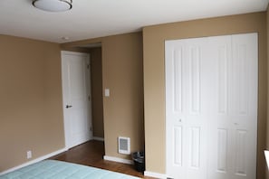 A room with beige walls, a white door, a white ceiling light, a vent, and a trash can. - Quiet Clean and Comfortable Room (Seattle)