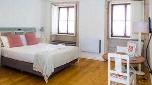A bedroom with a bed, bedside tables, a chair, and a window. - Liiiving in Porto - Historic Clerigos Studio 4F (Porto)