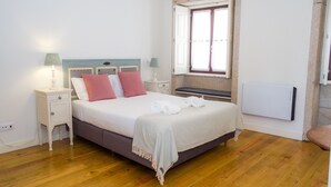 A neatly arranged bedroom with a bed, bedside tables, a lamp, and a window with curtains. - Liiiving in Porto - Historic Clerigos Studio 4F (Porto)