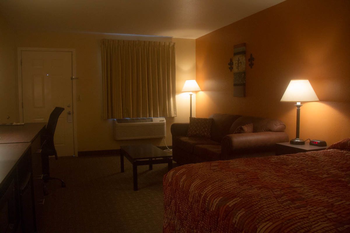 A hotel room with a bed, a desk, a chair, and two lamps.