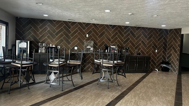 Cozinha moderna com revestimento em padrão herringbone, eletrodomésticos de aço inoxidável e uma ilha central com pia.