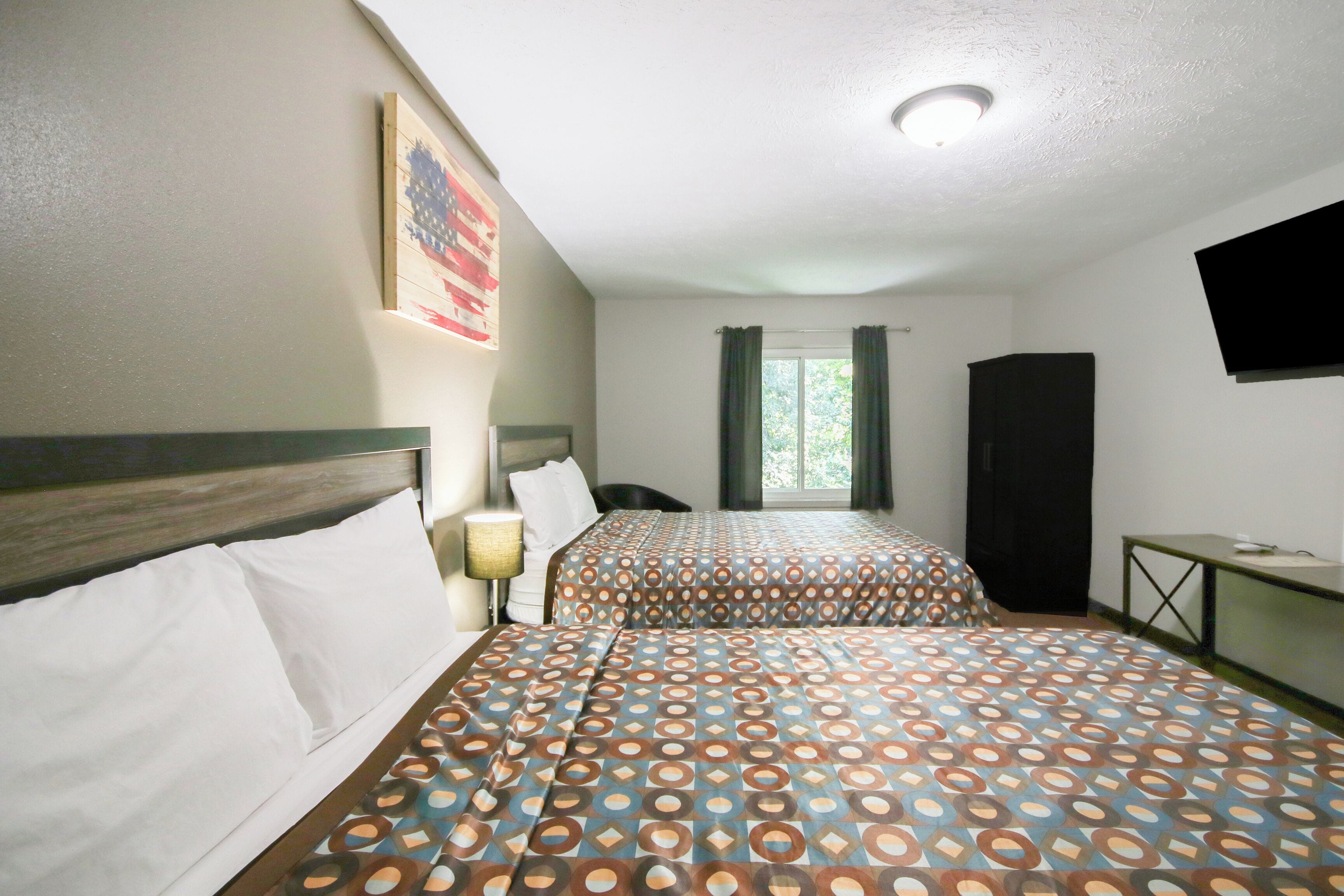 A hotel room with two beds, a TV, and a window with curtains.