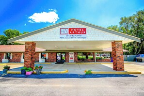 A hotel with a brick facade, a covered entrance, and a signboard displaying the name and contact information. - Hotel Arthur (Glenwood)