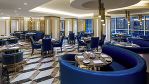Un restaurante moderno con asientos azules, pisos de mármol e iluminación contemporánea.