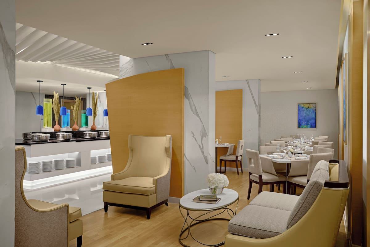 Un moderno vestíbulo de hotel con un área de descanso, un espacio para comer y un bufé.