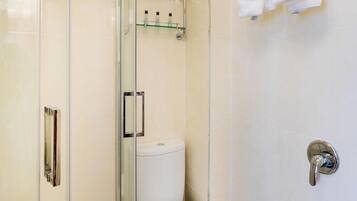 Un baño moderno con cabina de ducha de vidrio, inodoro, lavamanos y perchero para toallas.