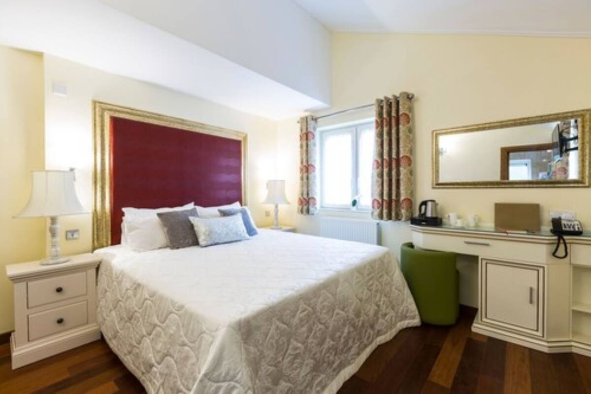 A neatly arranged hotel room with a bed, bedside tables, a desk, and a mirror.