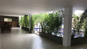 Um espaço amplo e interno com uma mesa de jantar e cadeiras, rodeado por plantas em vasos e uma escada.